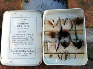 A tin of fly flies in a wooden box.