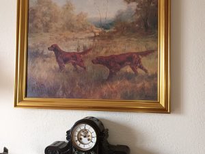 A painting of dogs on a mantle.