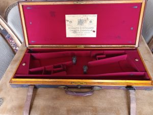 A brown leather case with a red handle, ideal for the Leather Holland & Holland Motor Gun Case.