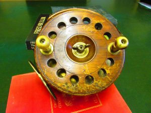 A wooden fishing reel sits on top of a book.